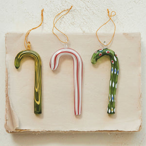 The CREATIVE COOP GLASS CANDY CANE ORNAMENT set features three festive styles—green with yellow swirls, white with red stripes, and green with colorful dots—all with hanging loops, perfect for holiday decorating.