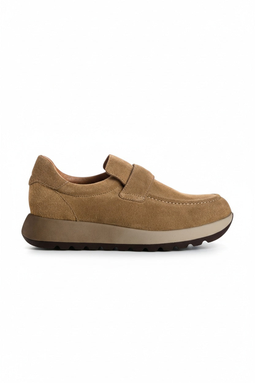 The REQINS - CARABEL Suede Sneaker in Havana is a tan goat suede casual-chic slip-on trainer featuring a rounded toe, wide instep strap, cushioned collar, and a thick dark rubber sole with a textured tread; shown in profile on a white background.