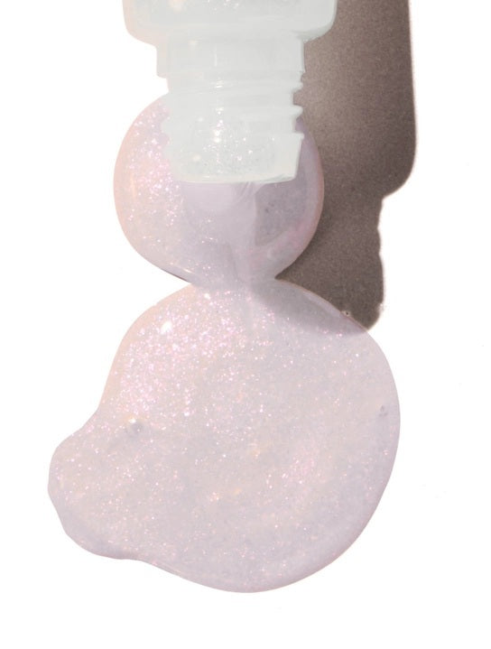 A close-up of a person smiling with glossy pink lips—enhanced by LANOLIPS - LIQUID LANOLIN LIP WATER from LANOLIPS—and smooth brown skin against a light blue background.