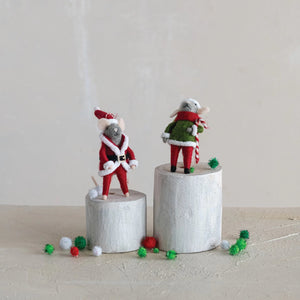 The CREATIVE COOP FELT MOUSE ORNAMENT set includes two handmade wool felt mice in festive outfits, standing on white wooden blocks with red, green, and white pom-poms against a neutral, minimalist backdrop.