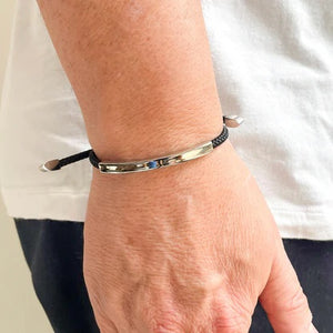 The STOLEN RICHES Algarve Bracelet in black features a braided cord with a sleek silver bar, silver end caps, and an adjustable sliding clasp for a minimalist look.