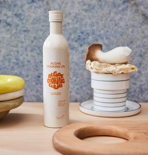 A white bottle labeled "Algae Cooking Oil – the Future of Healthy, Chef-Driven Oils" by ALGAE COOKING CLUB features orange design, product info, and a screw cap. This heart-healthy oil is great for high-heat cooking and shown on a white background.