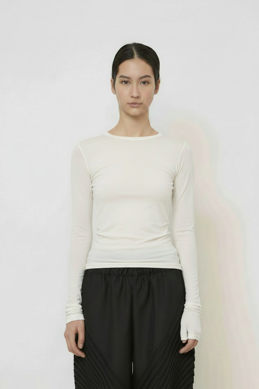 A woman with long dark hair in a low ponytail stands in profile against a plain light background, wearing the MEIMEIJ MESH LAYERING TOP by MEIMEIJ in red and a black skirt for a minimalist Italian fashion look.