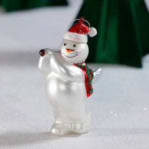 The ZODAX GLASS SNOWMAN PLAYING GOLF ornament, 3.5"x5.25", hangs by a silver string and features a smiling snowman in a red Santa hat and green scarf, holding one arm up as he plays golf.