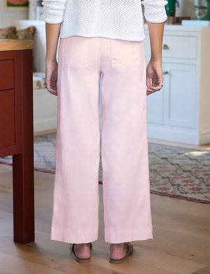 A person stands indoors wearing FRANK & EILEEN's Wexford Wide Leg Linen Pant in Ballet, crafted from Italian Performance Linen, paired with a white textured top.