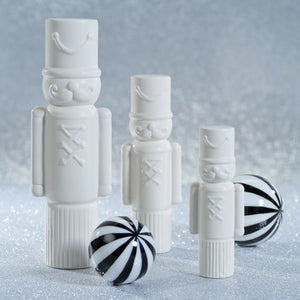 ZODAX DECORATIVE CERAMIC SOLDIER - MEDIUM white ceramic nutcracker figure measuring 3.5 inches by 9.5 inches, featuring a cylindrical hat, mustache, and button detail.