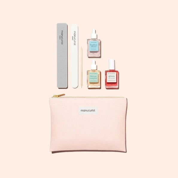 The MANUCURIST - GLOW MANICURE SET by MANUCURIST INC features a pastel pink zippered pouch, two nail files, and three bottles of vegan nail polish, all elegantly displayed on a light beige background.