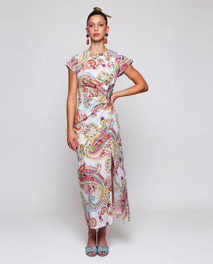 A woman stands against a white background wearing the MIRTO 1956 - PAISLEY PRINTED MIDI DRESS with short sleeves and light blue open-toe heels, her hair in a high bun.
