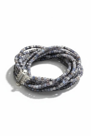 The ANN LIGHTFOOT Iolite Squares Ten Strand Bracelet features multiple strands of small, faceted square-cut blue and gray iolite beads with a silver slide clasp, shown against a white background.