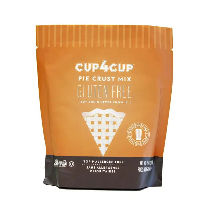 A bag of CUP4CUP GLUTEN FREE PIE CRUST by CUP4CUP, labeled gluten free and top 9 allergen free, features an image of a pie slice on the front. The orange and tan packaging with white and gold lettering highlights that this dairy free pie crust is an option everyone can enjoy.