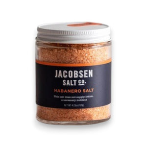 A small jar of JACOBSEN SALT CO. JACOBSEN SALT - INFUSED HABANERO SALT with a white lid sits on a light-colored surface against a plain, light gray background, ideal as spicy salt or for rimming cocktails.