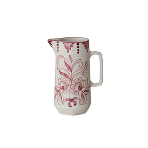 The HAND-PAINTED STONEWARE PITCHER WITH BOTANICAL DESIGN by CREATIVE COOP features a white ceramic finish, handle, and pink floral and swirl patterns with decorative dots, capturing charming cottagecore style on a plain background.