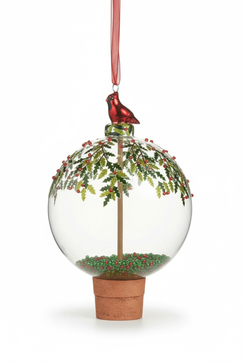 RAZ IMPORTS Cardinal and Holly Ball Ornament featuring a clear glass ball containing a miniature holly tree in a terracotta pot, topped with a red cardinal resin figurine and a red ribbon hanger.
