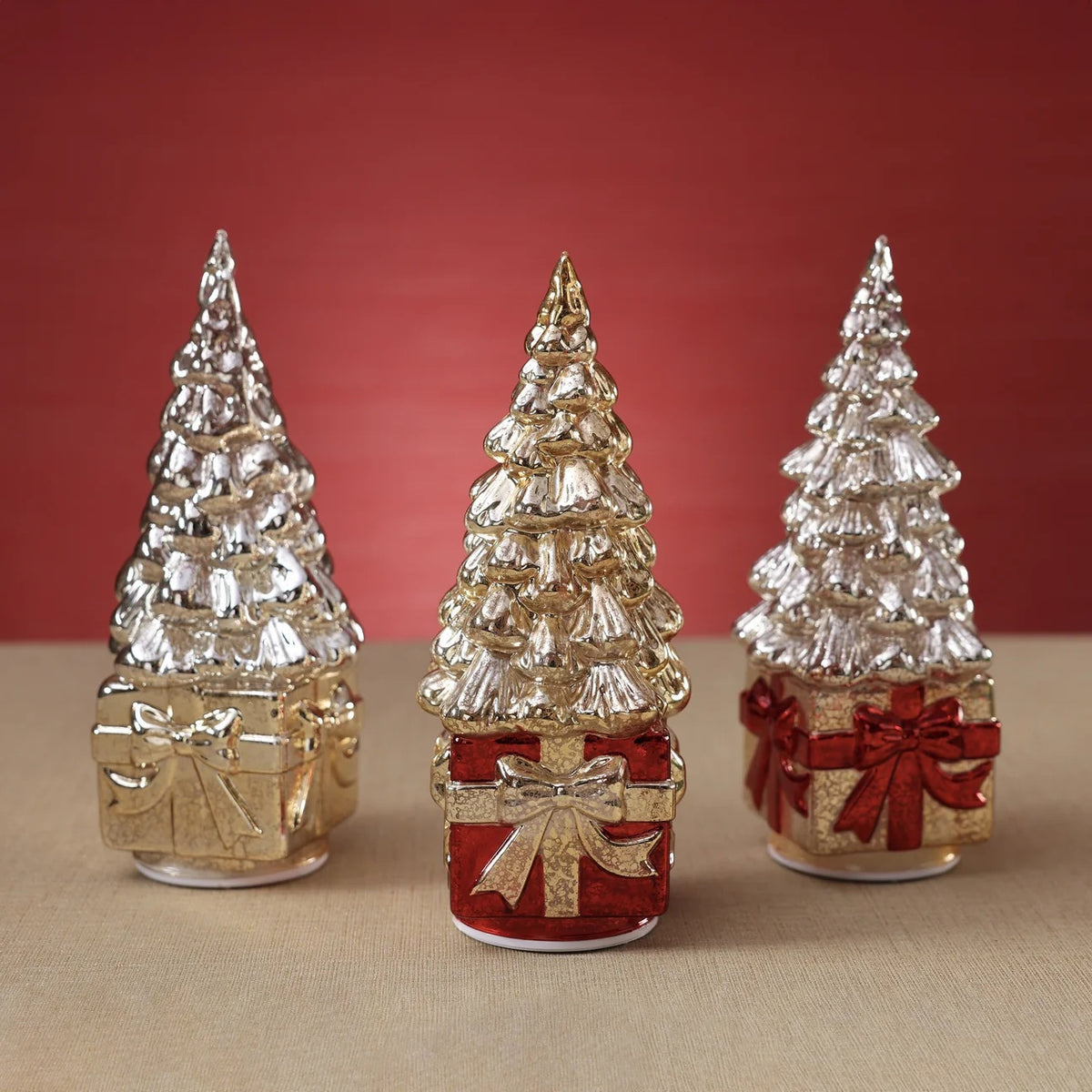 A ZODAX LED ROTATING TREE ON PRESENT, featuring a decorative glass Christmas tree with a light-up finish, sits atop a red gift box base accented with a gold ribbon.