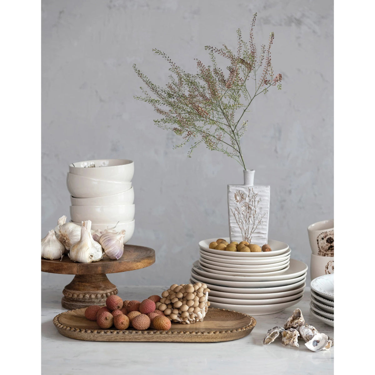 Introducing the Creative Coop &quot;Mango Pedestal with Wood Beads,&quot; a wooden cake stand crafted from 100% mango wood. This elegant stand offers a round, flat surface perfect for holding cakes or desserts and features a decorative carved base adorned with circular bead patterns near the top. The natural finish of the mango wood beautifully showcases its unique grain and texture.