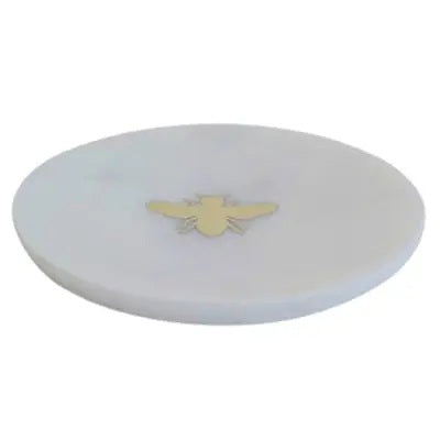The HOMART MARBLE TRAY INLAID WITH BRASS BEE is a round, white marble tray featuring a small brass bee at the center and measures 6 inches in diameter.