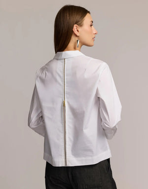A woman stands against a plain, light background wearing the HINSON WU Alessa 3/4 Sleeve Shirt in stretch polished cotton—a crisp white blouse with a collared neckline and partial front zipper—paired with dark pants.