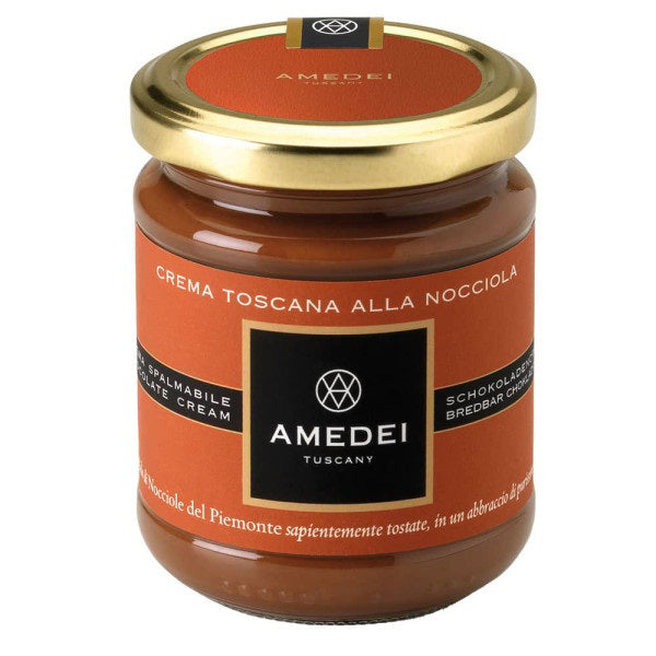 An image of a jar of AMEDEI - CREMA TOSCANA GIANDUJA CLASSIC by ATALANTA CORPORATION, made in Italy. The jar features a gold lid and an orange and black label with white text. This Gianduja spread is crafted with Tonda Gentile Trilobata Hazelnuts, as indicated by the multilingual text on the label.