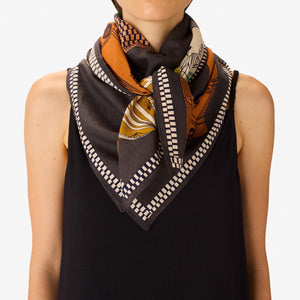 The INOUI EDITIONS - TEQUILA SCARF IN LEMON by INOUI features vibrant cacti and succulents in green, yellow, and white on brown and gray pedestals, set against a dark gray background with a decorative border.