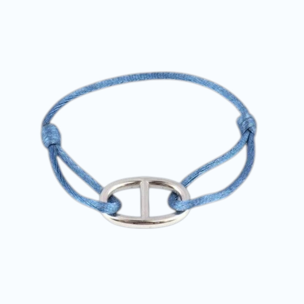 A close-up of a wrist wearing the STOLEN RICHES Viseu String Bracelet with Anchor Chain Fixture in light blue, paired with a light blue shirt and dark pants, highlights this nautical accessory from STOLEN RICHES.