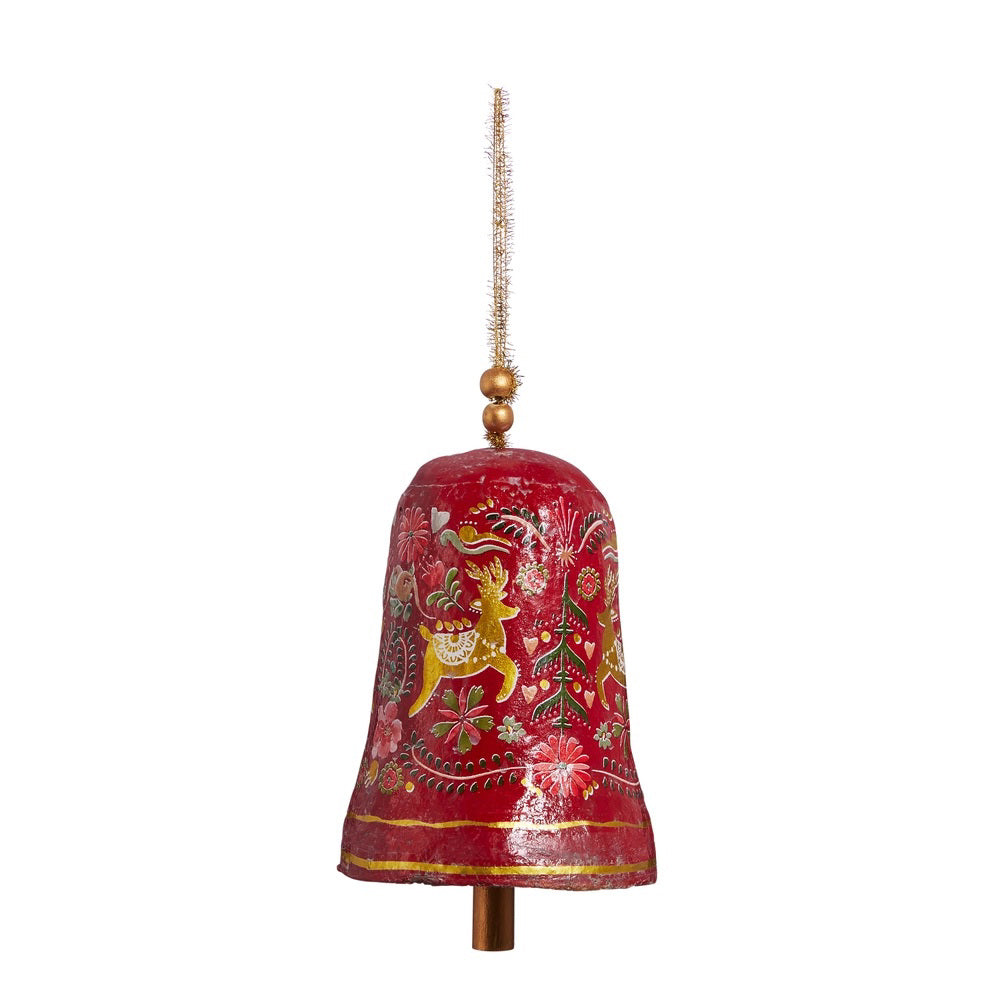 The FOLKLORE REINDEER ORNAMENT by RAZ IMPORTS is a red bell with gold and white reindeer and floral designs, hanging from a gold string next to a festive paper vase.