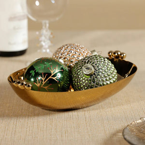Introducing the POLISHED GOLD SERVING BOWL by ZODAX, an elegant oval-shaped brass bowl with decorative round handles on each end, showcased gracefully against a white background.
