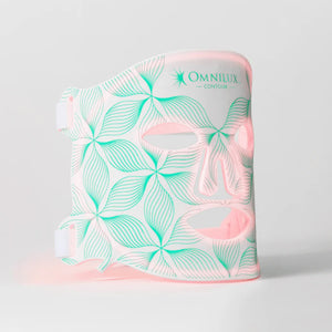 The OMNILUX - CONTOUR FACE MASK by OMNILUX, designed for skin rejuvenation and anti-aging, features red light therapy technology. It has adjustable straps, cutouts for eyes, nose, mouth, and a geometric green-white pattern on a plain white background.