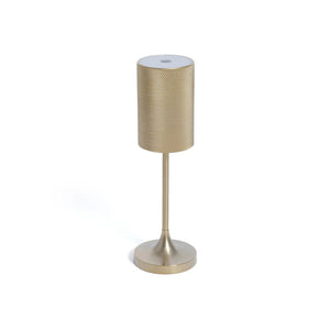 The FACET RECHARGEABLE LAMP by ZODAX is a modern gold table lamp with a textured cylindrical shade, slender stem, and round base. It offers adjustable light intensity and is displayed against a plain white background.