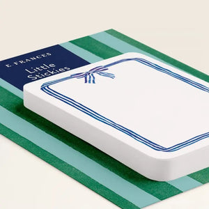 A pack of E. FRANCES PAPER "LITTLE STICKIES BLUE RIBBON" watercolor sticky notes featuring a blue ribbon border, displayed on green and dark blue striped packaging.
