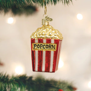 Old World Christmas POPCORN ORNAMENT glass ornament shaped like a red and white striped popcorn snack bucket with the word “POPCORN” printed on the front.