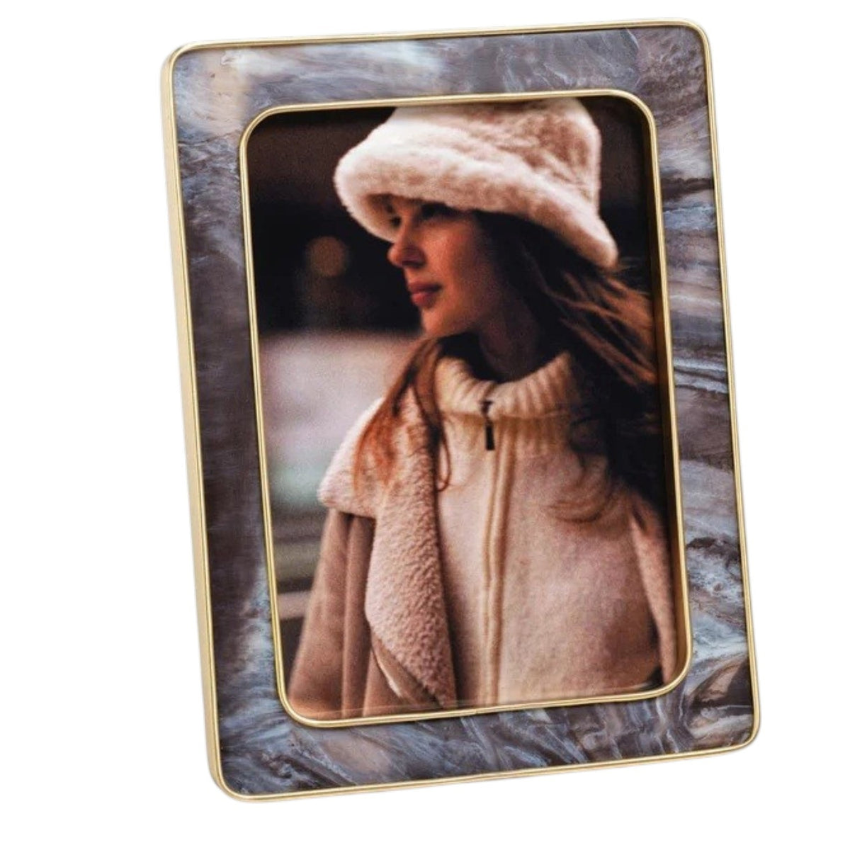 A portrait of a woman in a white fuzzy hat and coat, displayed in the ZODAX Marbled Hazel Resin Frame with Antique Brass Trim (5x7), featuring a rectangular contemporary design with marbled gray-blue edges and a gold-toned border.