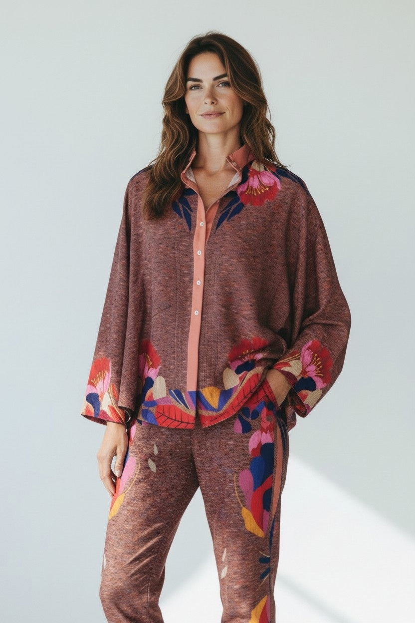 A woman poses against a light background in the FRANCO FERRARI Long Sleeve Silk Print Blouse, featuring a relaxed maroon fit with artistic floral details on the sleeves, cuffs, and matching pants.