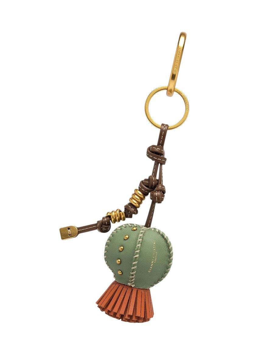 The GIANNI CHIARINI CACTUS KEYRING / BAG CHARM is a round green leather accessory with gold studs, brown accents, red fringe, and a gold keyring and clasp. Perfect as a stylish keychain or bag charm.