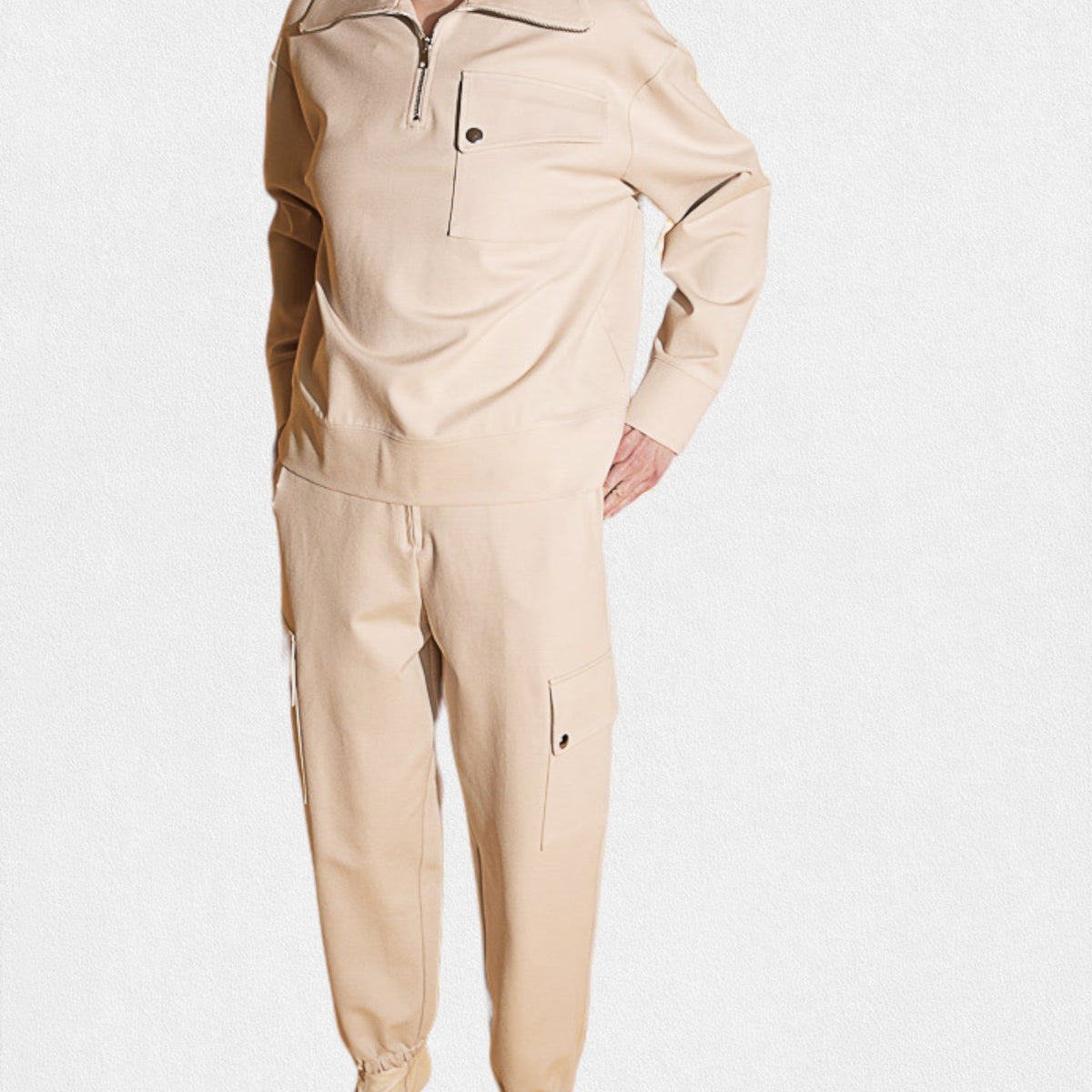 Someone dressed in MEIMEIJ - JOGGER PANT, showcasing patch pockets and elastic cuffs in beige. The jogger pant is paired with a beige top against a plain white background.