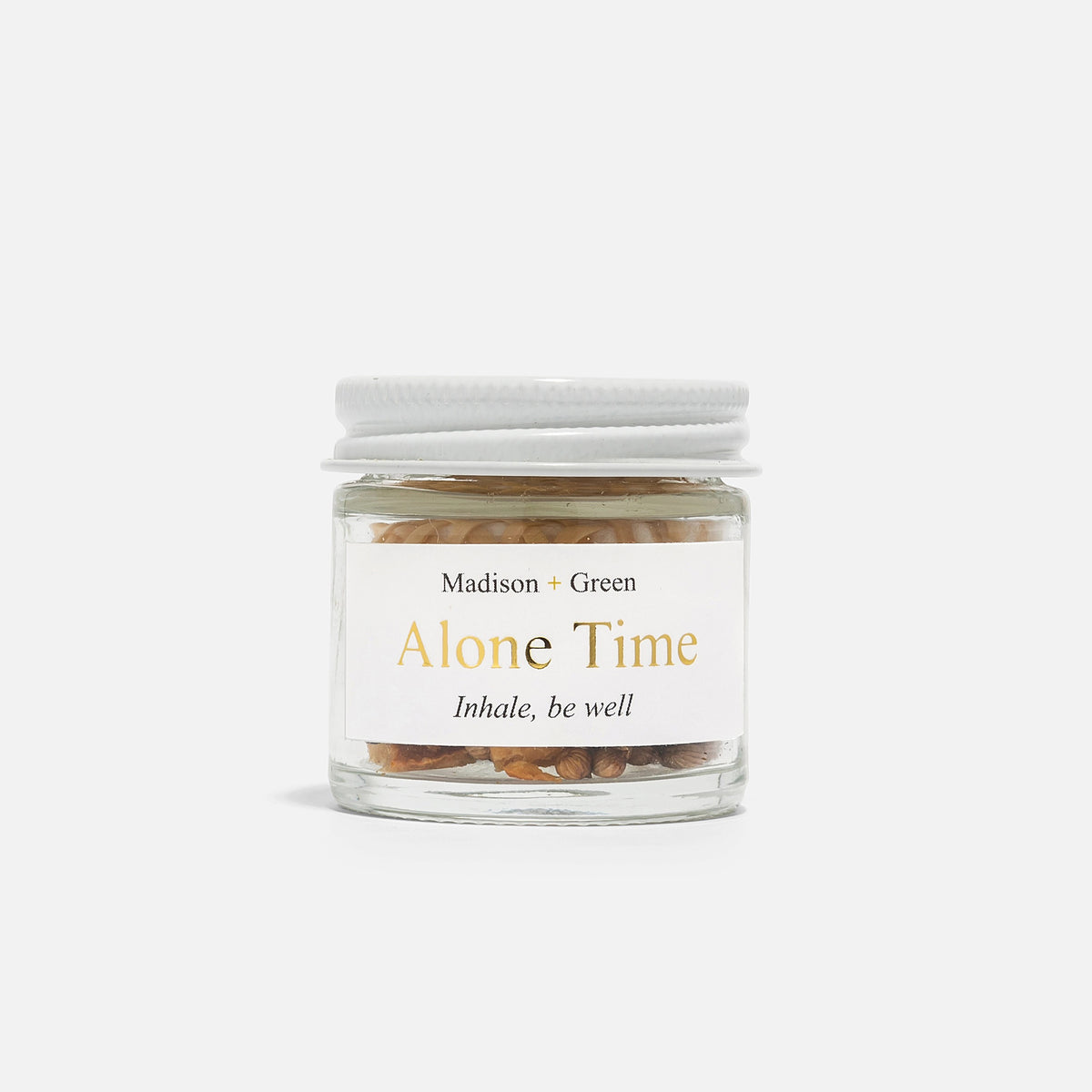 The MADISON GREEN ALONE TIME AROMATHERAPY INHALER is a small glass jar with a white lid, featuring a stress-relief blend of herbs and organic essential oils—perfect for aromatherapy.