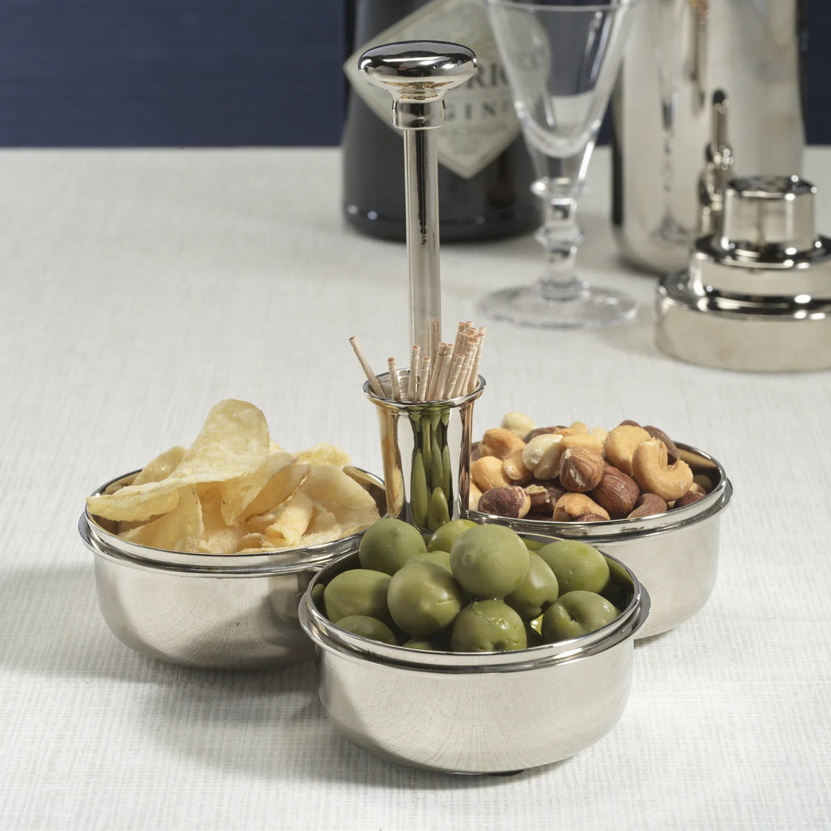 The ZODAX BASSO CONDIMENT TRIO WITH COCKTAIL PICK HOLDER is a durable stainless steel 7.75-inch serving tray featuring three round bowls and a central handle, ideal for serving snacks or condiments.