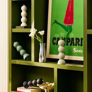 A bright dining table displays an ADDISON ROSS SCANDI BOBBIN Salt or Pepper Mill, a glass vase with green leaves, a bowl of figs, limes on a plate, a wine glass, and a yellow napkin on a set plate.