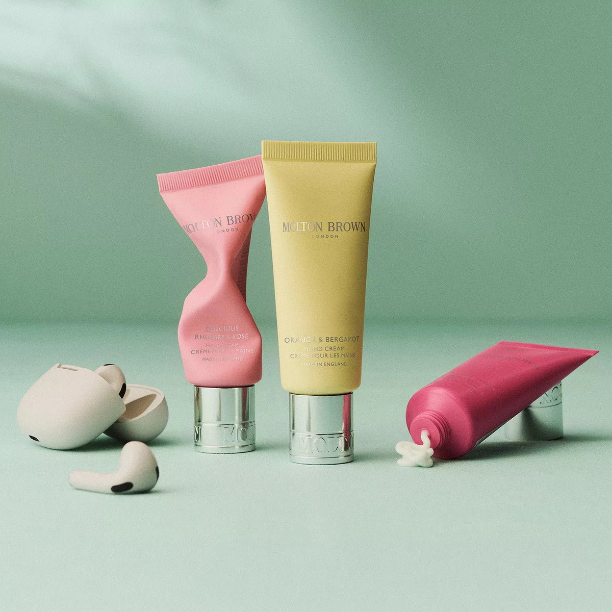 A yellow tube of MOLTON BROWN - ORANGE & BERGAMOT HAND CREAM with a silver cap, featuring fresh citrus musk notes, stands upright on a white background.