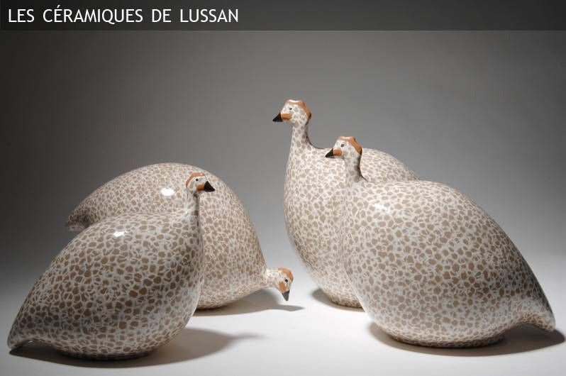 Four large ceramic pecking French guinea fowl in white with black spots are displayed against a neutral background. The text &quot;Les Céramiques de Lussan&quot; appears at the top left corner, showcasing exquisite handmade pottery from France.