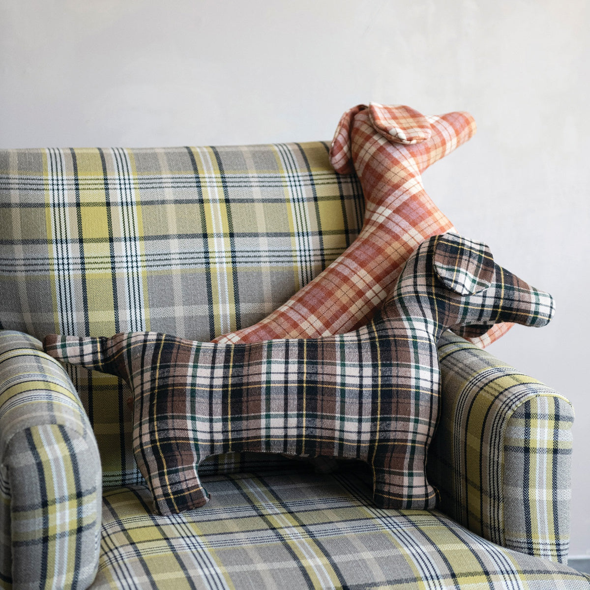 The CREATIVE COOP PLAID DOG-SHAPED PILLOWS, shown here in brown-green and red-orange patterns on a white background, bring cozy farmhouse style to any space.