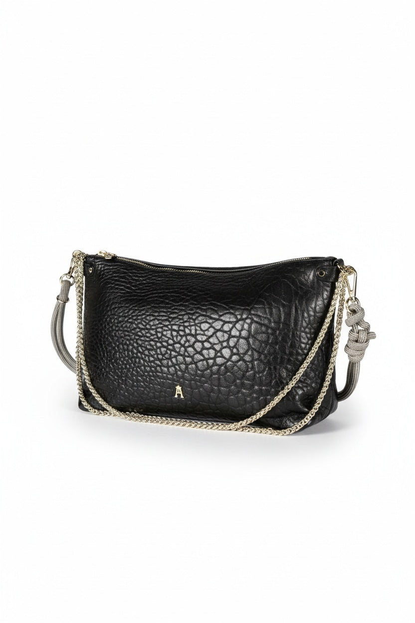 The CRAIE STUDIO - MALLOW BUBBLE NOIR HANDBAG features black bubble leather, a luxurious gold zipper, and an elegant gold chain strap. Displayed against a white background, this chic piece from CRAIE STUDIO adds sophisticated style to any outfit.