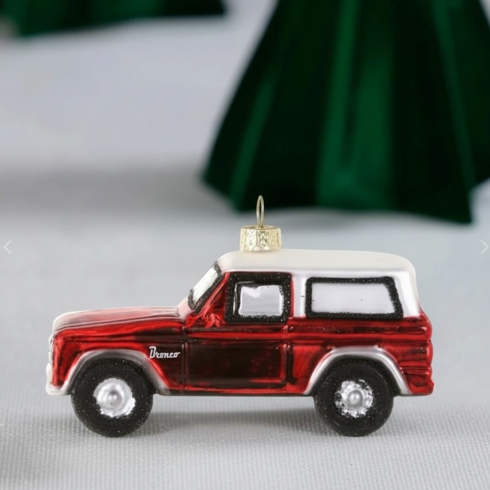 A 4-inch decorative red and white GLASS VINTAGE TRUCK ORNAMENT by Cody Foster, hanging by a gold thread.
