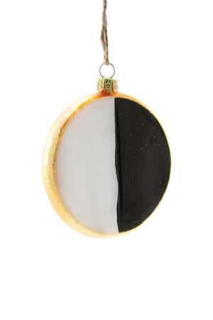 The CODY FOSTER BLACK AND WHITE COOKIE ORNAMENT is a 3.5-inch glass ornament with white and black halves, gold edging, a gold cap, and hangs by a string.