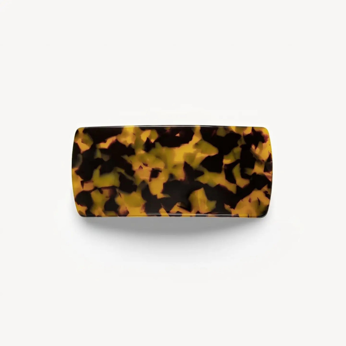 A person with brown wavy hair in a low twist, secured by the MACHETE - JUMBO BOX BARRETTE IN TORTOISE, is seen from behind wearing gold hoop earrings and a black top.