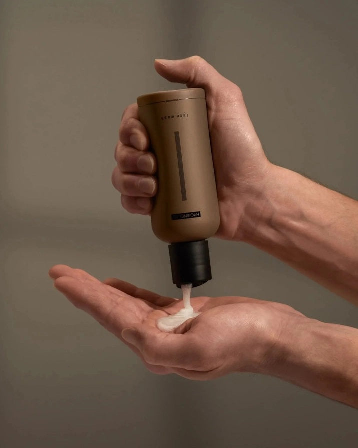 A tan bottle of HYGIENELAB FACE WASH, UNSCENTED, featuring a black cap and minimalist label with vertical black lines on the front, formulated with niacinamide to promote a balanced and refreshed complexion.