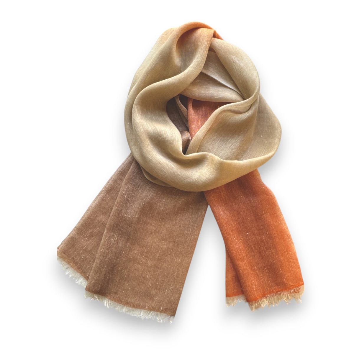The BAJRA Hand Dyed Linen Blend Scarf in Burnt Orange Ombre is a handmade piece with a gradient from beige to brown to orange. The fabric, similar to delicate pashmina, is soft and sheer with frayed edges for a casual and cozy look.