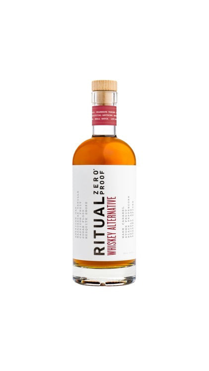 A bottle of RITUAL ZERO PROOF-WHISKEY ALTERNATIVE caters to health-conscious consumption. The bottle has a white label with &quot;RITUAL ZERO PROOF&quot; in black text and &quot;Whiskey Alternative&quot; in red text. The cap is topped with a red seal, and the alcohol-free whiskey inside is amber-colored.
