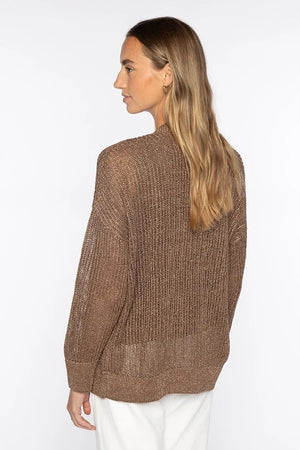 A woman with long, light brown hair wears the KINROSS CASHMERE Open Texture Lurex Linen Cardigan over a matching top and white pants. She stands against a white background, one hand in her pocket, smiling softly.