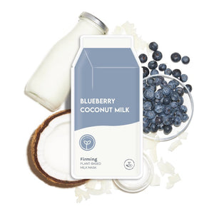 A carton labeled "ESW BEAUTY - BLUEBERRY COCONUT MILK MASK" by ESW BEAUTY sits among a milk bottle, blueberries, coconuts, and coconut flakes on white—perfect inspiration for a blueberry coconut plant-based sheet mask.