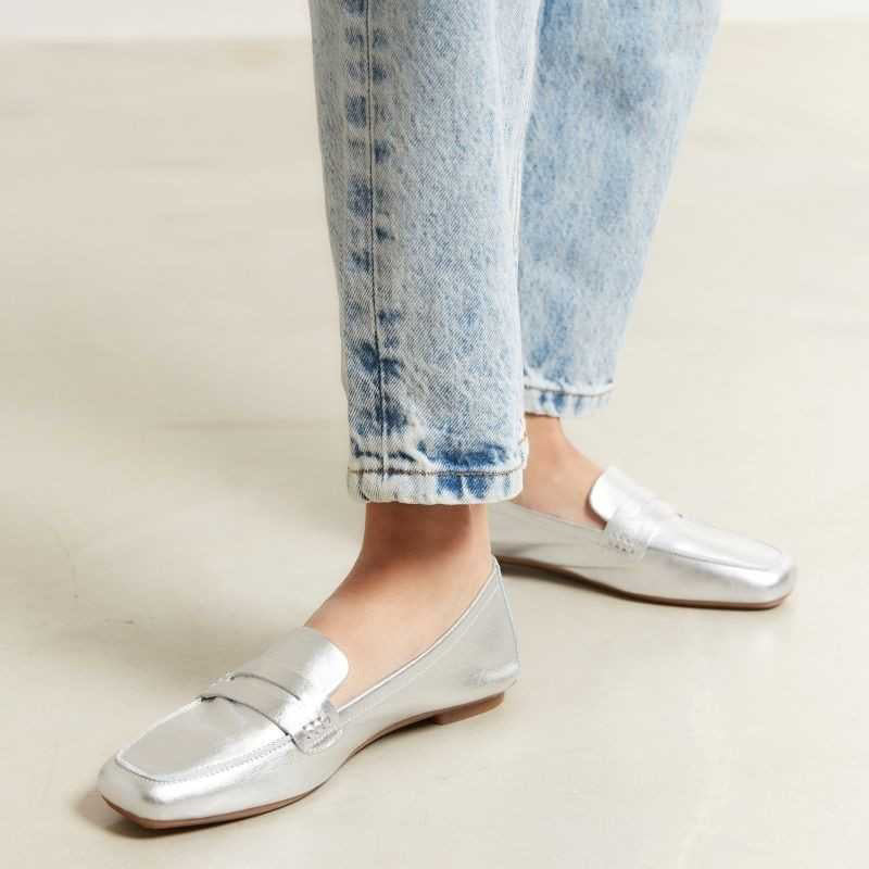 The REQINS HEMA Metallic Loafer in Silver is photographed from above on a light background, revealing its shimmering leather and the brand’s name visible on the dark insole.